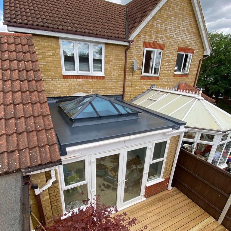 Modern brick home with white conservatory extension featuring glass roof panels and wooden deck