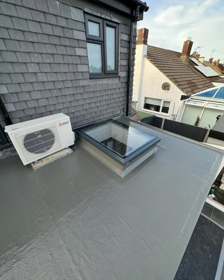 Flat roof of modern extension with heat pump unit, skylight, and surrounding residential rooftops visible.