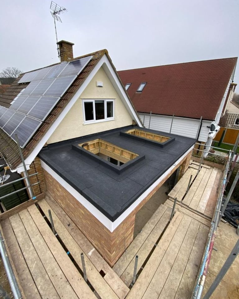Aerial view of residential rooftop with solar panels, skylight openings, and brick chimney